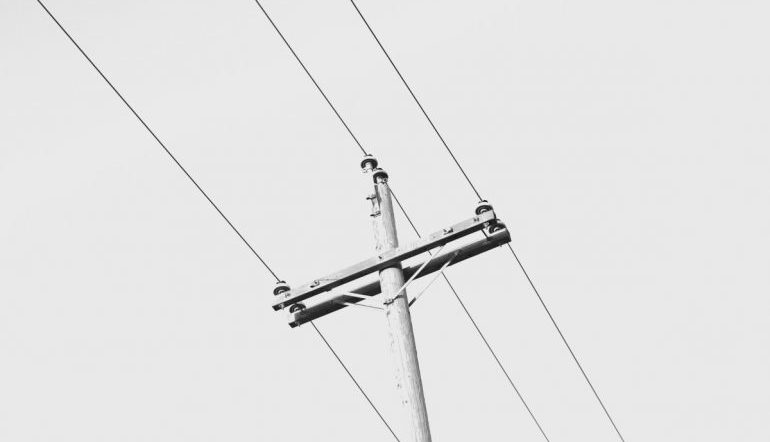 view from the ground of a telephone pole with wires