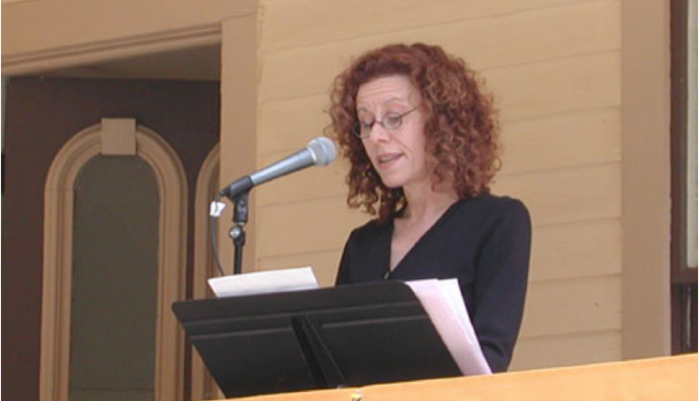 woman speaking at a stand with a microphone