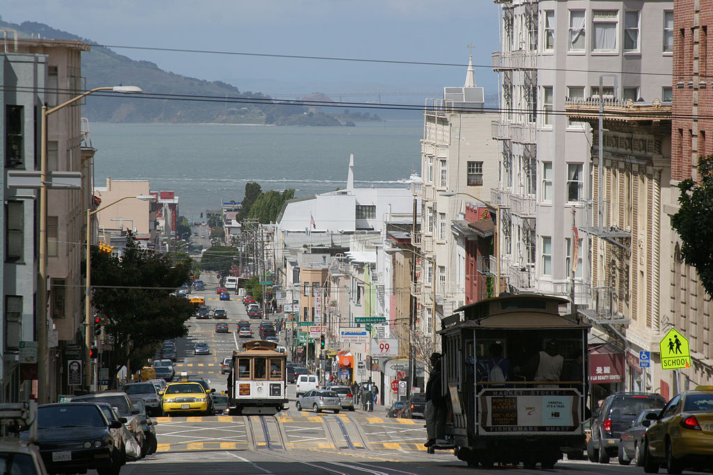 Photograph of the view from the top of Nob Hill, showing a hilly street with streetcars 