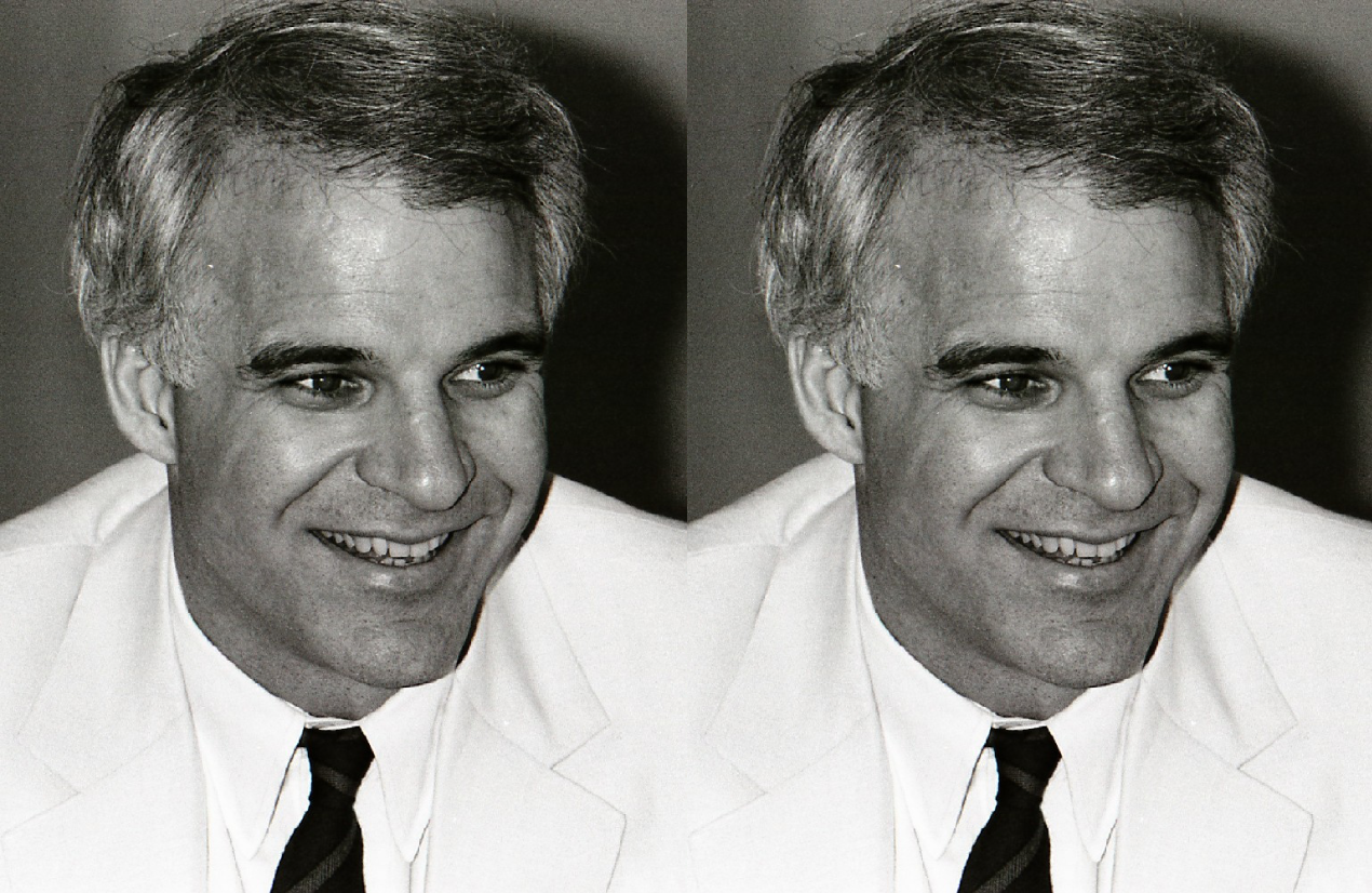 Black and white photograph of Steve Martin smiling in a suit and tie