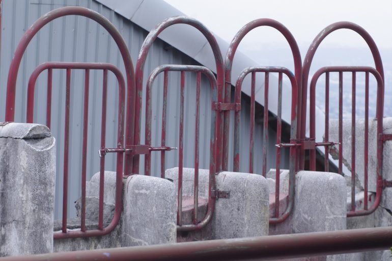 image shows a series of red, rusting gates side by side