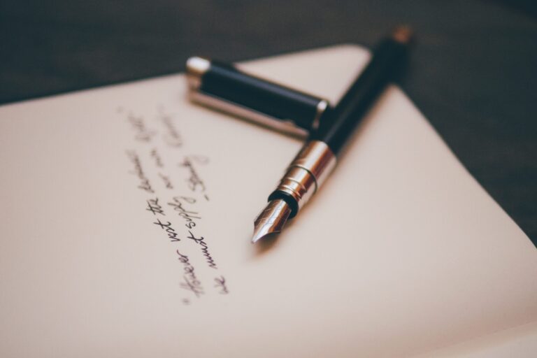 A black fountain pen sits atop a half-written letter.