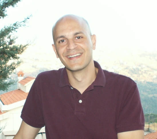 image of Fady Joudah, who poses for the portrait in a maroon golf shirt