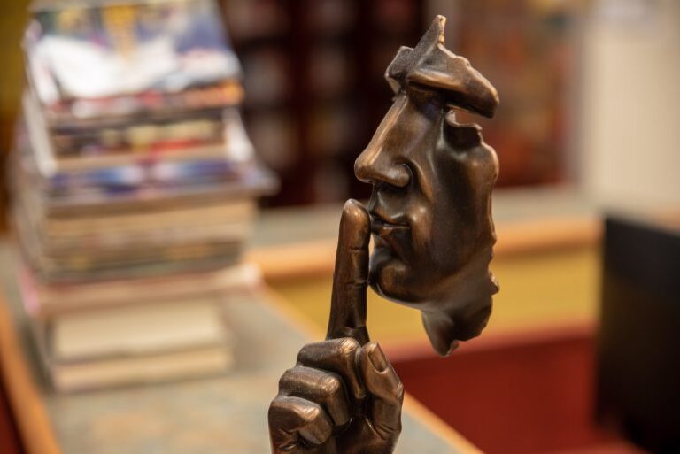 Statue of a face with a finger over its lips