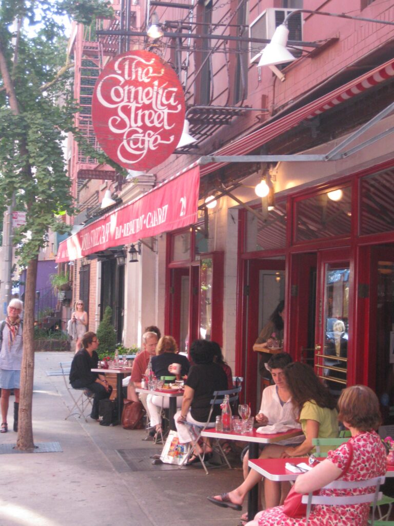 street view features a cafe with people sitting outside on the sidewalk