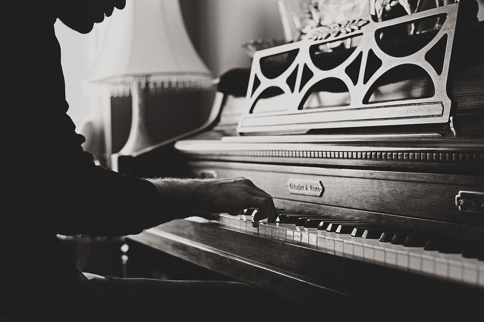 black and white photograph of a silhouetted man sitting and playing piano
