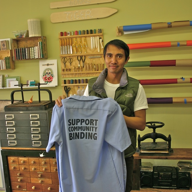 photo of a man in a green vest holding up a blue shirt