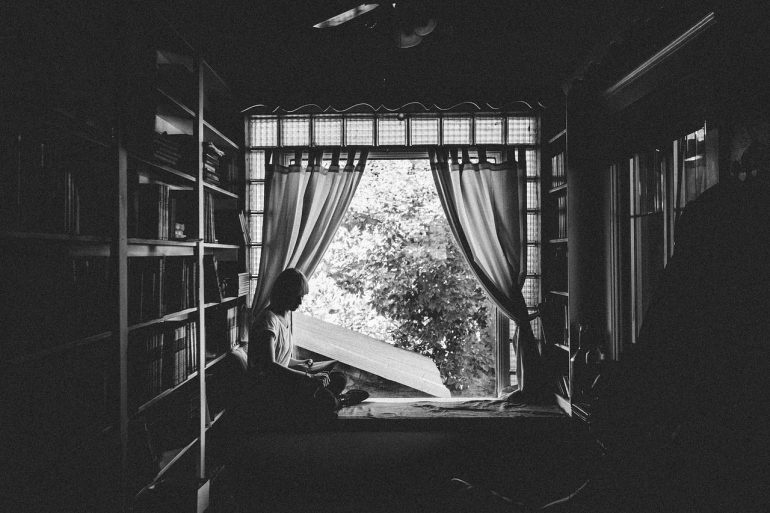 Girl reading by a curtain