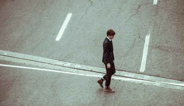 A person walking alone on a street, dressed in a suit 
