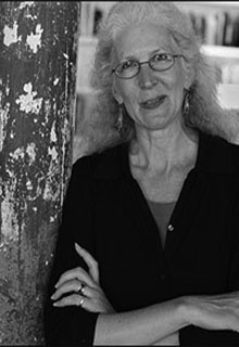 A black and white image of a white woman smiling with her arms crossed