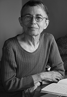 A black and white image of a white woman sitting in front of an open book