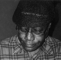 A black and white image of a black man looking at the ground