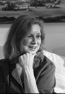 A black and white image of a white woman smiling and sitting on a couch