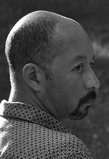 A black and white image of a black man looking over his shoulder