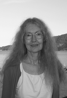 A black and white image of a white woman smiling in front of a body of water