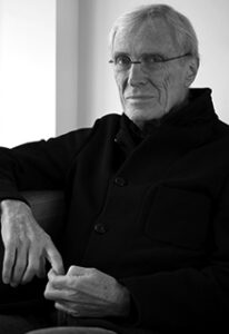 A black and white image of a white man wearing glasses and a black shirt