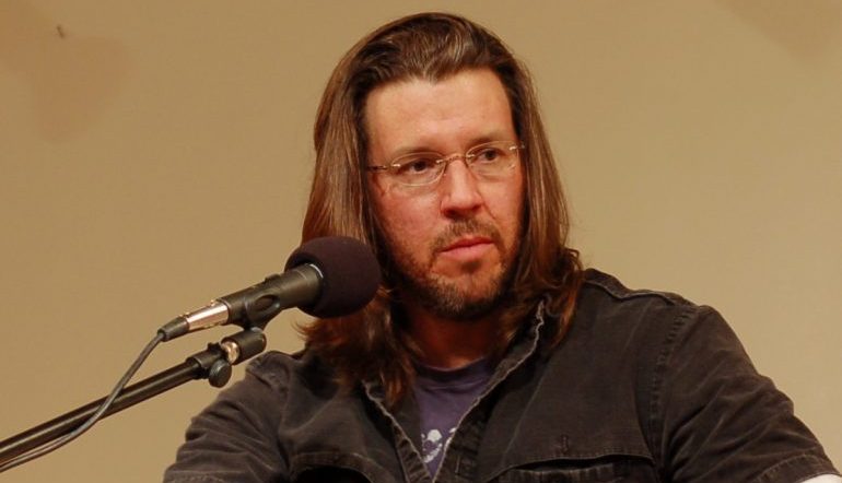 A picture of David Foster Wallace sitting in front of a microphone