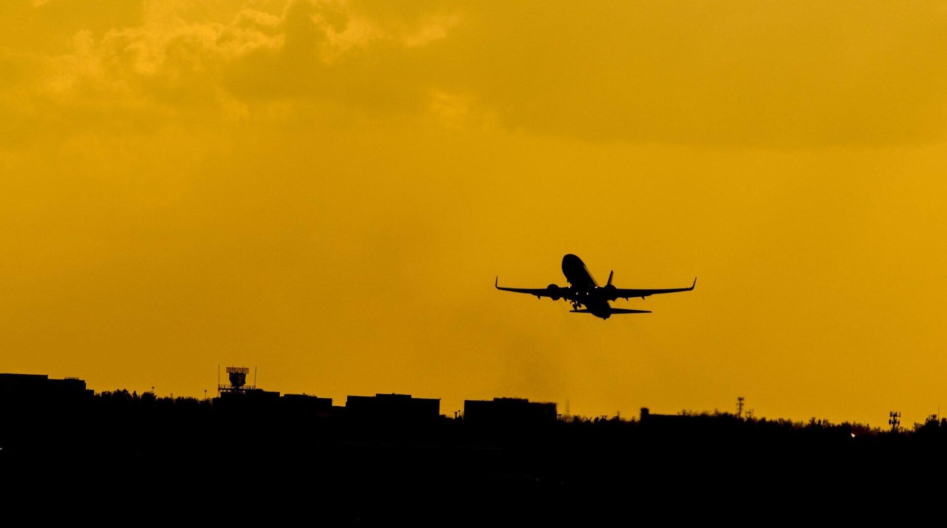 Plane flying against a yellow sky