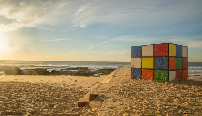 Rubik's Cube partially buried in the sand at the beach