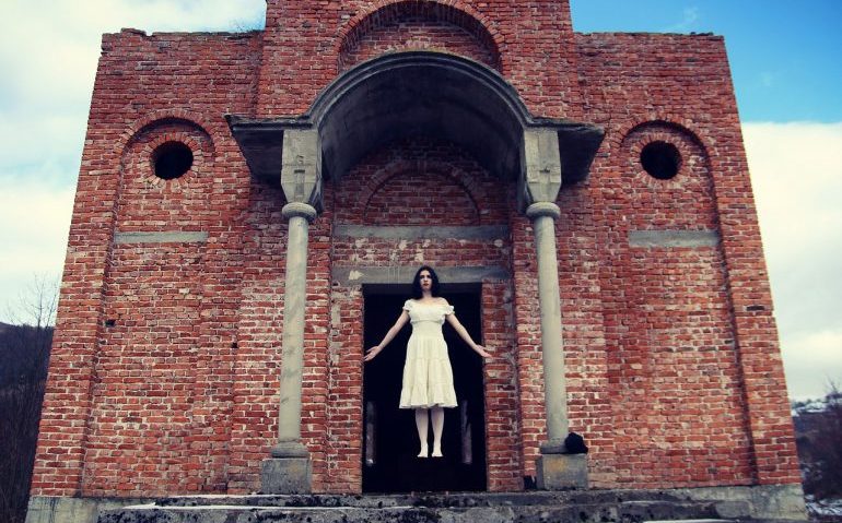 Picture of a woman levitating in front of an old brick building.