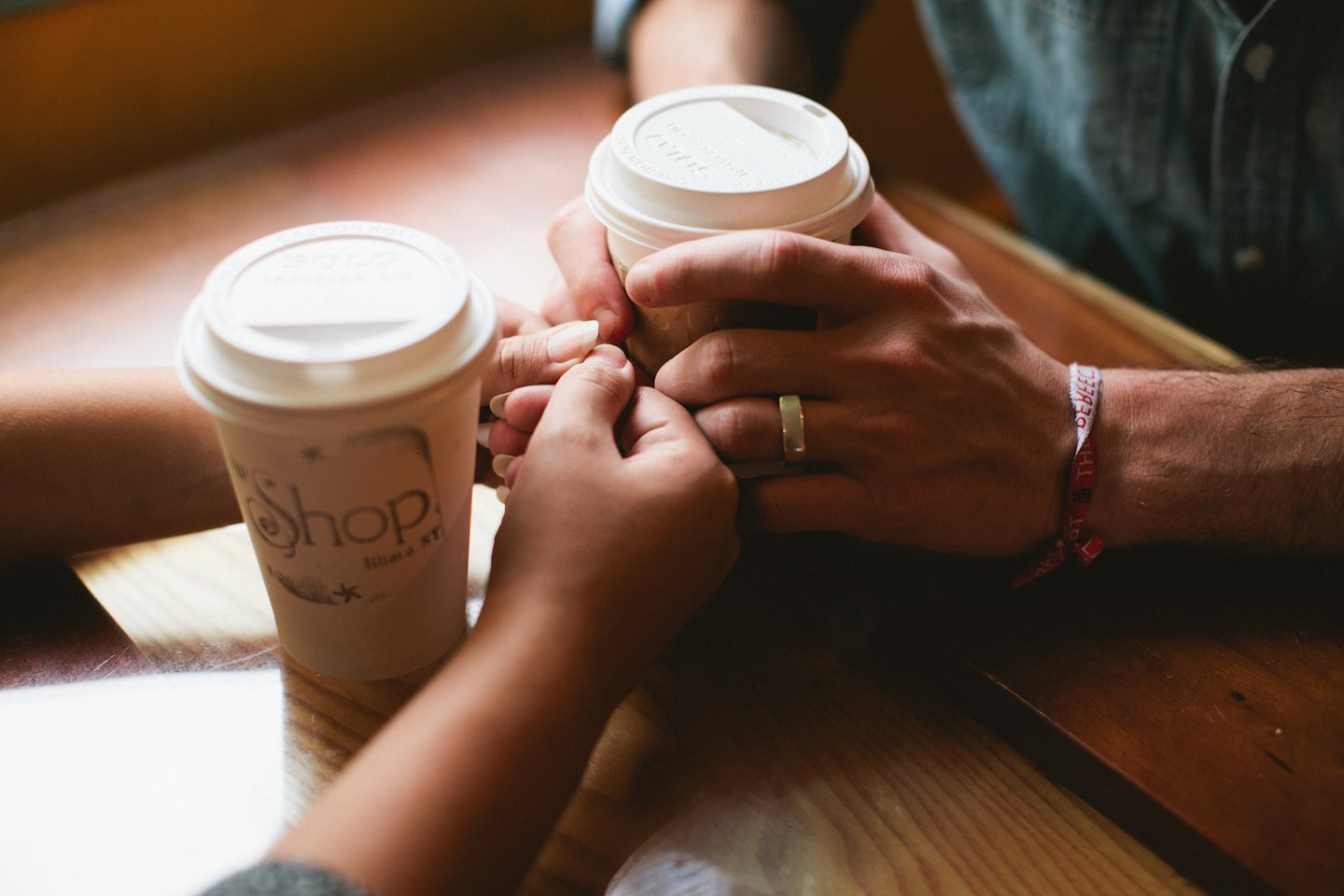 hands touching while holding cups of coffee