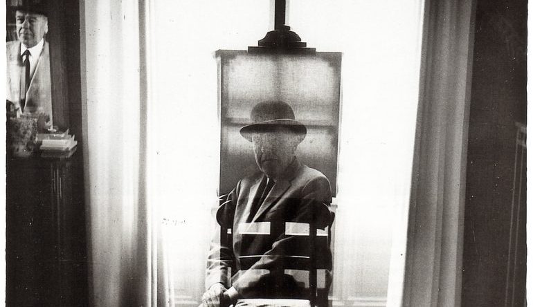 Black and white picture of a man, his face overlayed in front of an easel