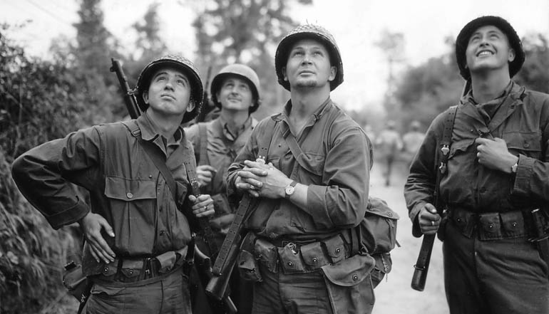 Black and white picture of a group of soldiers looking up into the sky.
