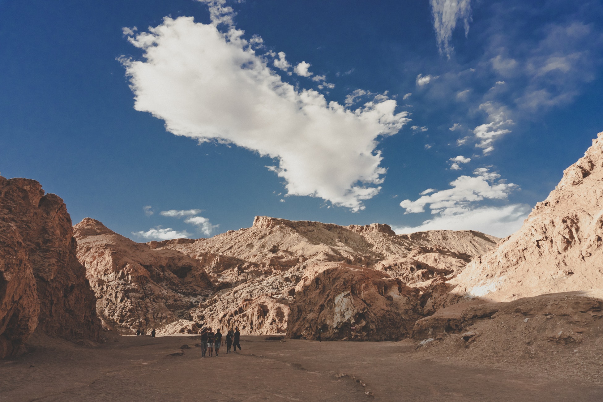 Men walking around in desert under blue sky.