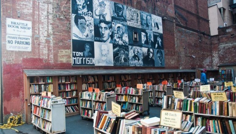Picture of the Brattle Book Shop in Boston. A lot of bookshelves on the outside of the store. 