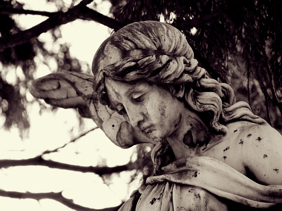 Close up picture of an angel statue with a sad expression. 