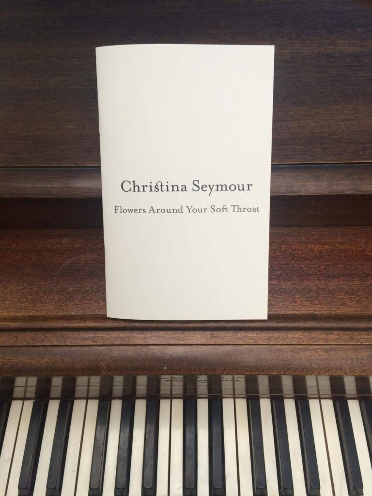 Picture of a Christina Seymour, Flowers Around Your Soft Throat booklet on top of a piano
