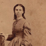 Sepia toned photograph of a woman in a historical dress.