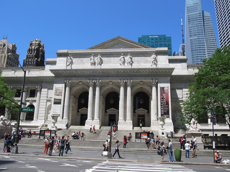 Street view of the New York Public Library, a large white building with columns in the front.