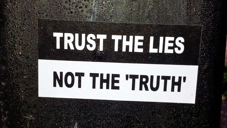 Text that reads "Trust the Lies Not the 'Truth'" on a black and white background.
