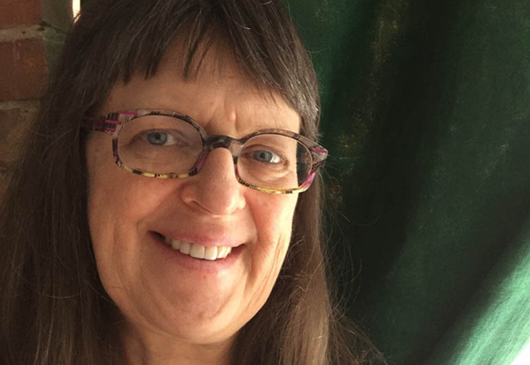 Photo of a woman with bangs wearing glasses and smiling at the camera.
