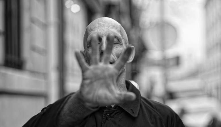 A man holding up a hand in front of his face.
