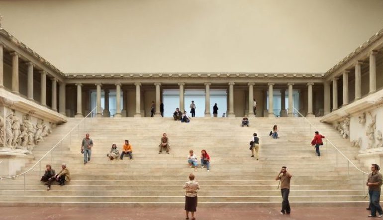 people sitting on wide steps inside a museum