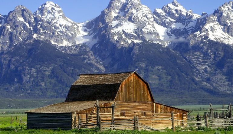 wooden barn in front of snow-capped mountains