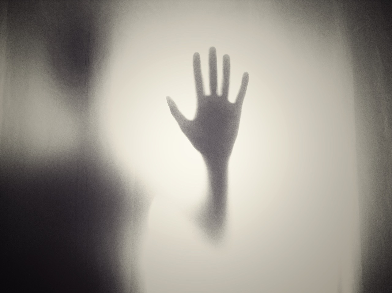 A hand is pressed against foggy glass.