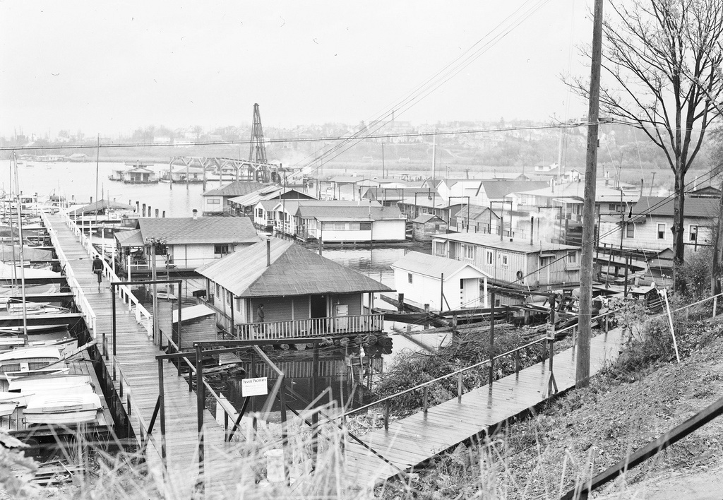 A black and white photo of old house boats on the water.