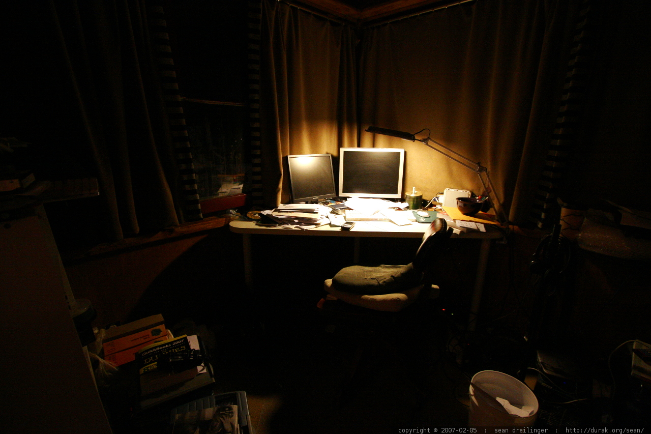 photo of a messy desk illuminated only by a small lamp
