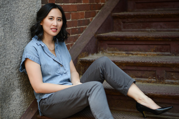 An Asian American woman sits on a staircase.