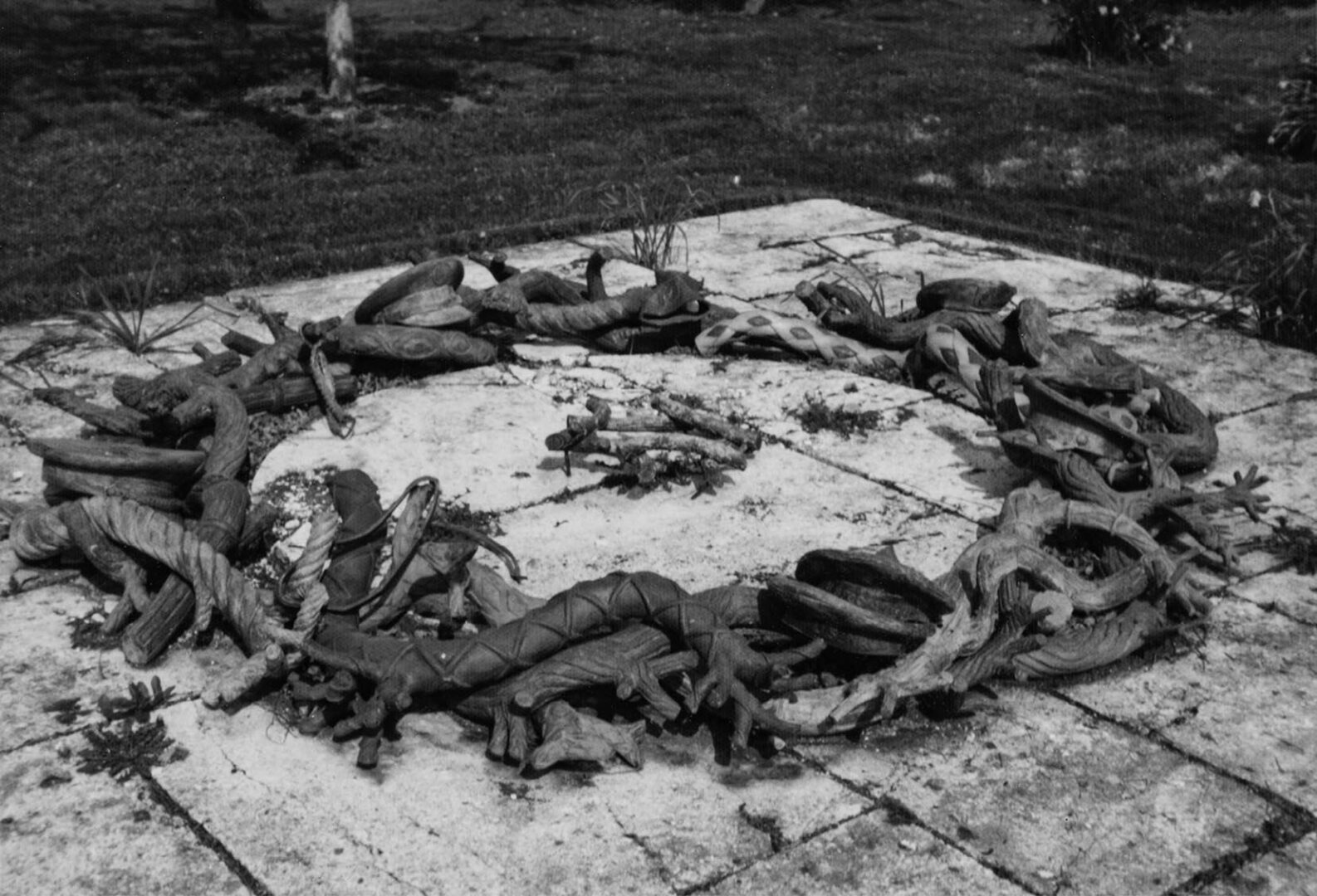 Circular wreath with intertwined branches and military hats on a stone surface viewed from a sideways angle.