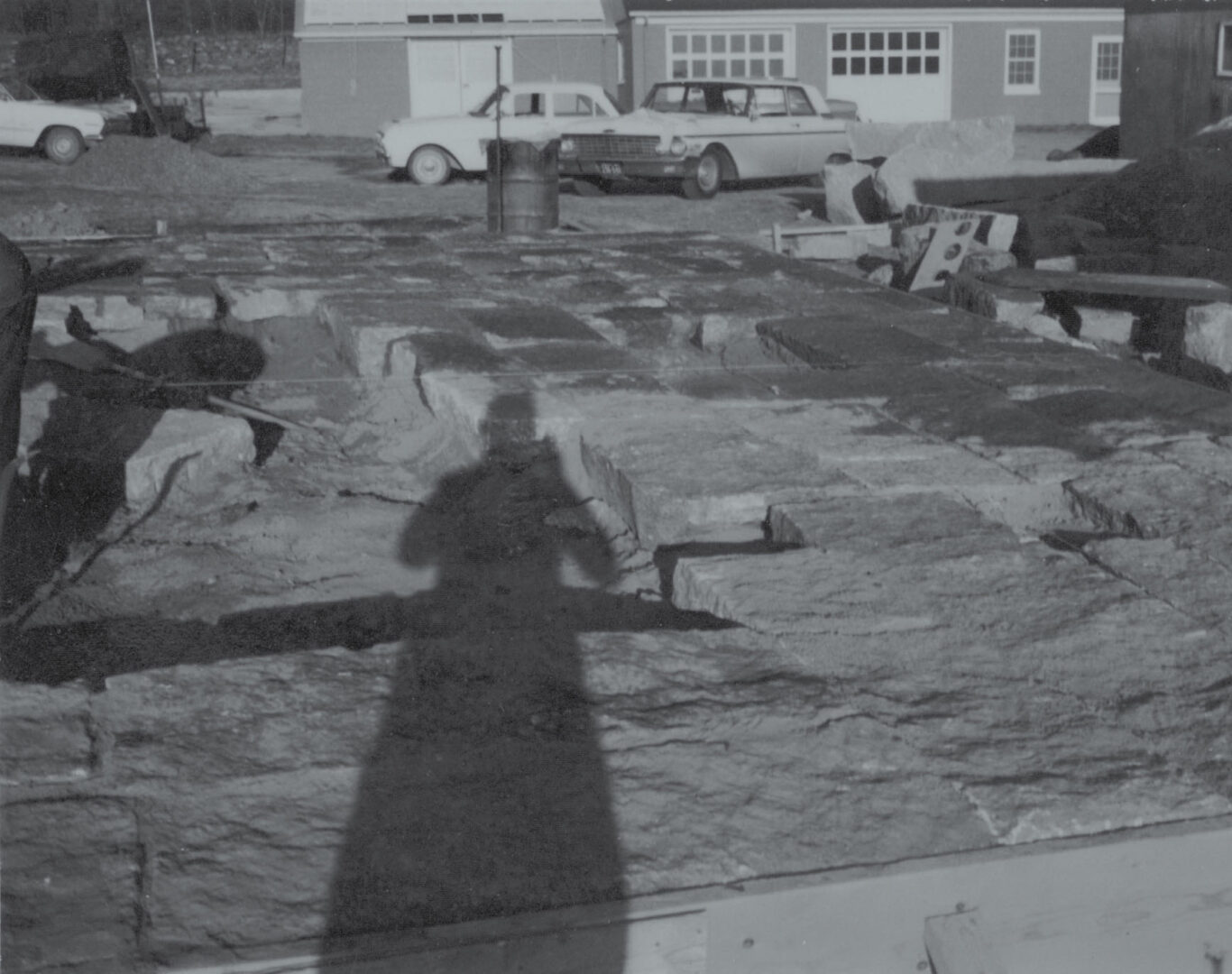 Black and white photo of a stone yard. A shadow of a person holding a camera is visible on the stones.